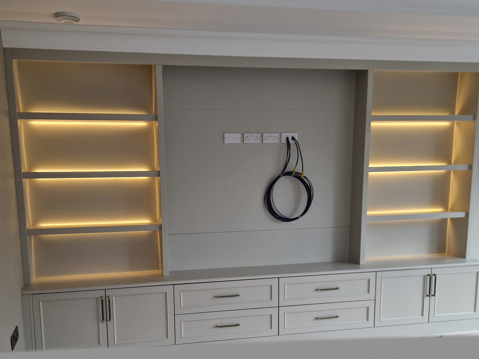 Bespoke painted media wall with LED-lit floating shelves and integrated cabinets